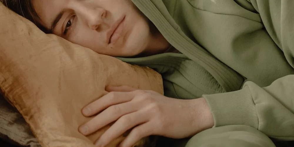 Person resting on a light beige sofa, wearing a green hoodie