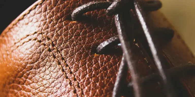 Close-up of brown leather with visible grain, stitching, and laces.