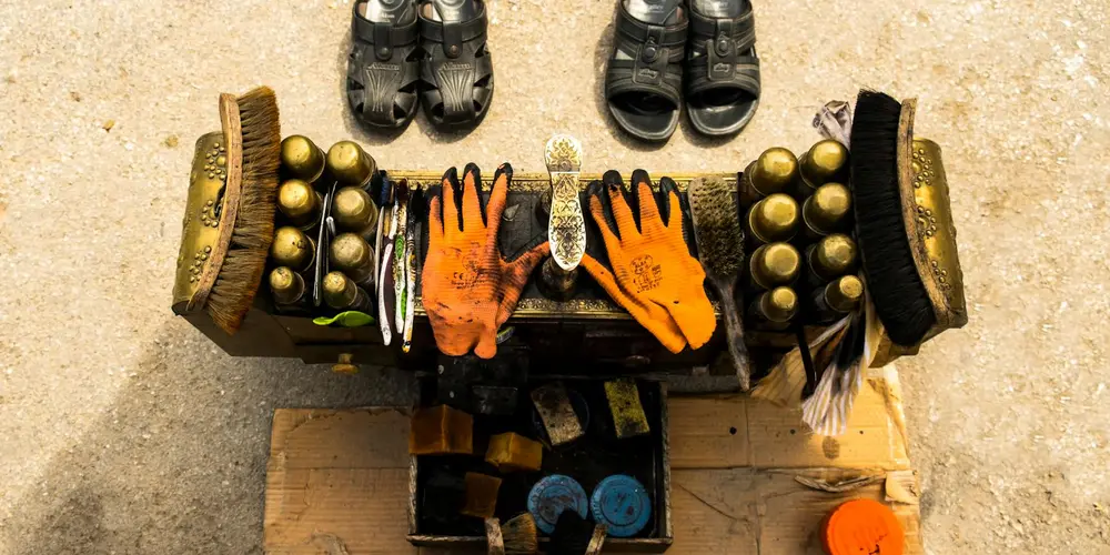 Leather cleaning tools and protective gloves arranged on a workbench, with brushes and small bottles, illustrating DIY leather care