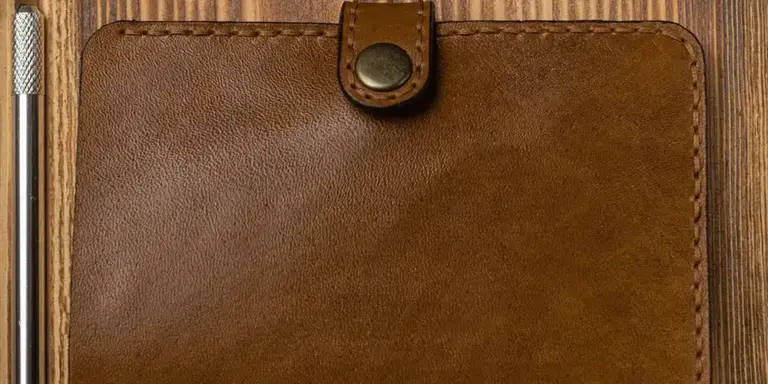 Close-up of a brown leather wallet on a wooden surface.
