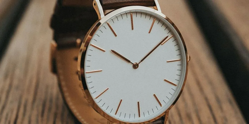 Close-up of a brown leather watch strap attached to a white-dial wristwatch.