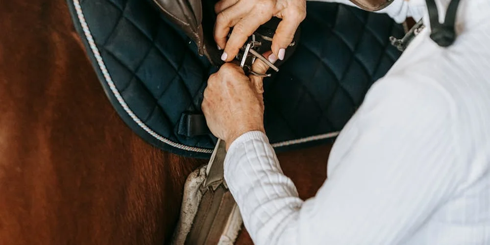 Close-up of hands applying a water protectant to leather gear (saddle).