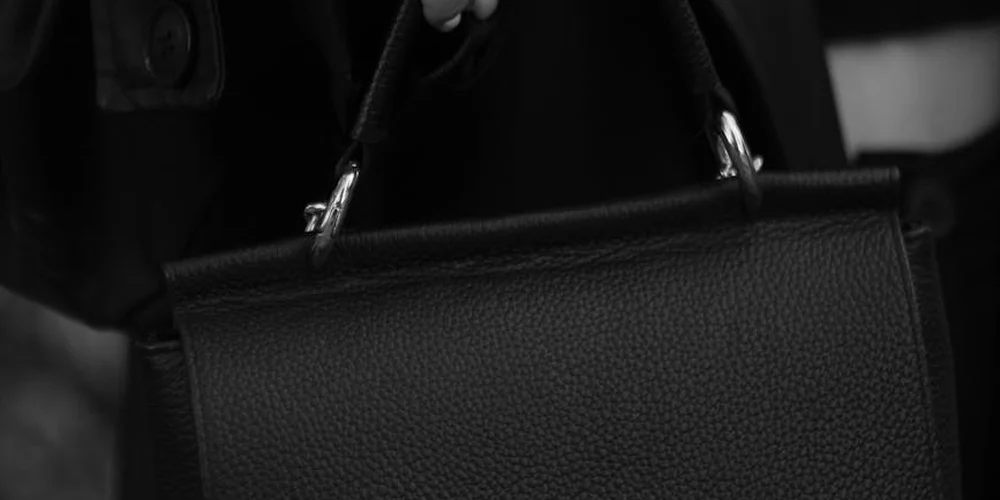 Close-up of a black textured leather handbag with handles