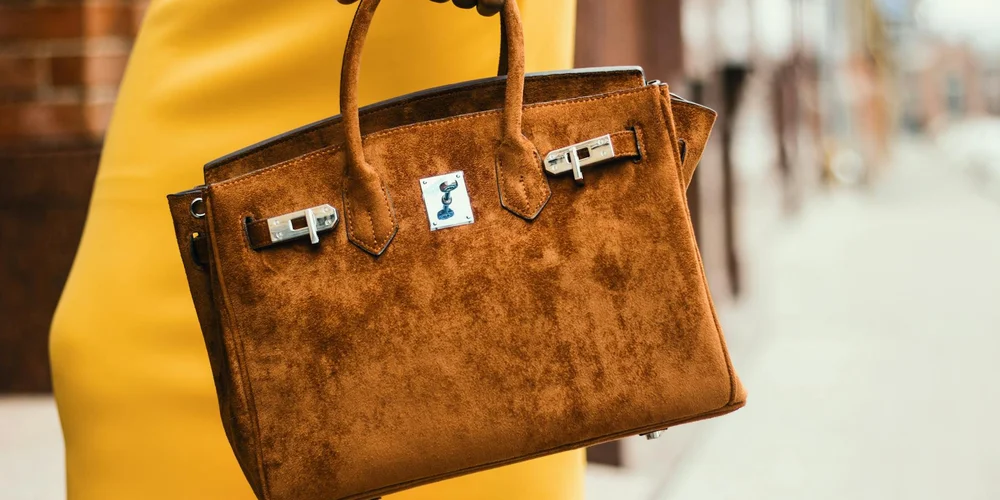 Distressed brown leather handbag on a city sidewalk.
