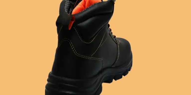 Black leather boot with orange lining displayed on a tan background.