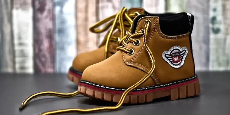 Tan leather work boots with yellow laces and a rugged rubber sole, showing textured leather and stitching.