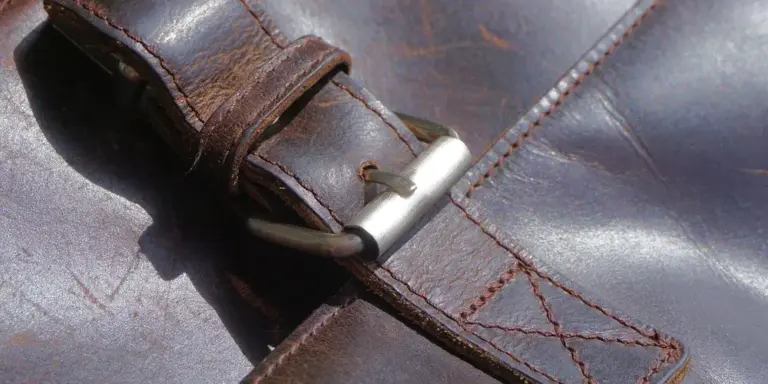 Close-up of a worn leather strap with a metal buckle