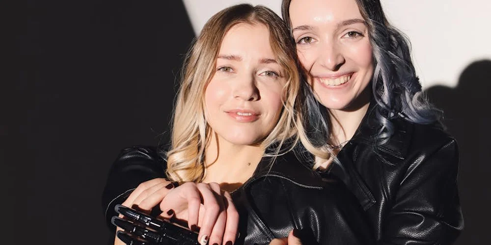 Two women wearing black leather jackets smiling at the camera