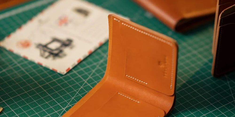 Open leather wallet resting on a green cutting mat, showing neat stitching and a clean interior, illustrating routine long-term maintenance.