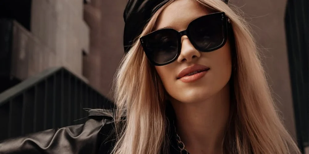 Person wearing a black leather jacket and sunglasses in an urban setting, illustrating durable leather care.