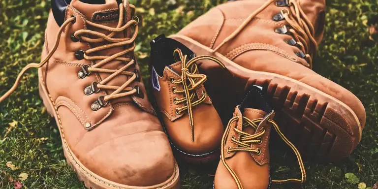 Tan leather hiking boots on grass with laces and rugged soles