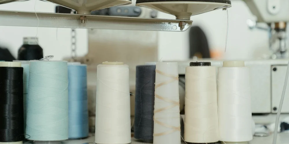 Assorted thread spools arranged in front of a sewing machine, ready for leather sewing setup.
