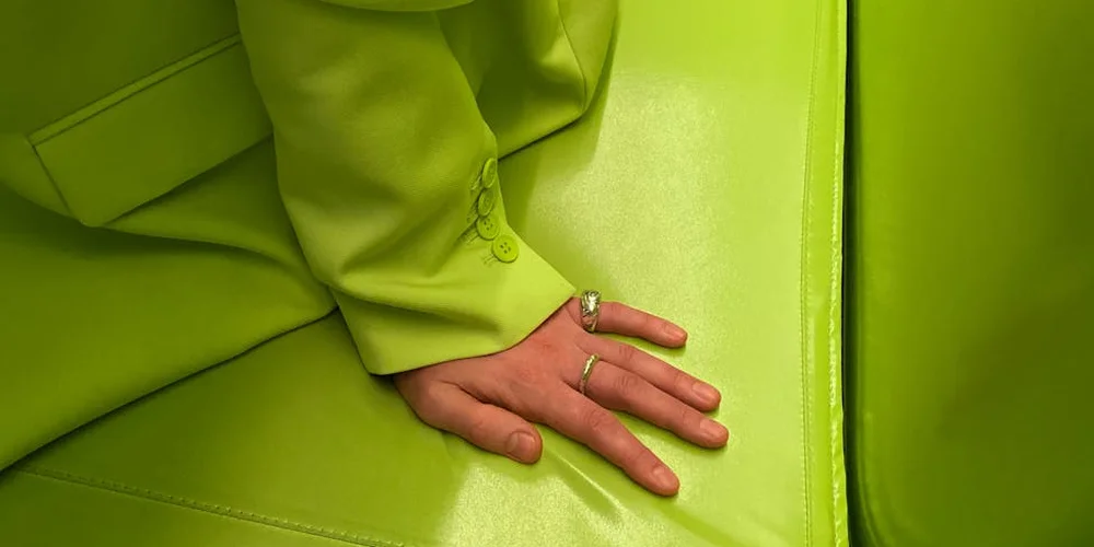 Close-up of a hand resting on a lime-green leather surface, showing texture and stitching.
