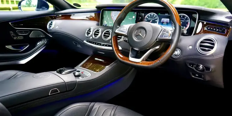 Interior of a luxury car with leather seats, wood trim, and a steering wheel.