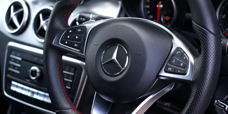 Close-up of a leather-wrapped Mercedes steering wheel inside a luxury car