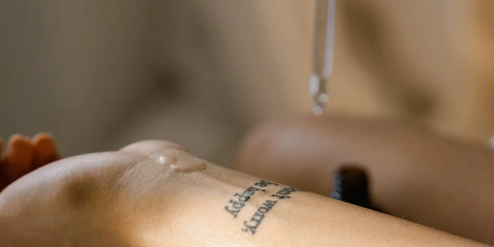 Close-up of a tattooed skin surface with a metallic instrument hovering above, suggesting a processing or treatment step.