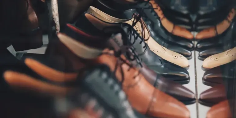 Assorted leather dress shoes in brown, tan, black, and oxblood arranged together on a surface.
