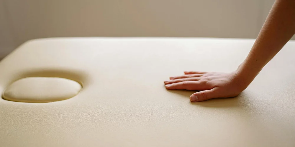 Close-up of a hand resting on beige leather upholstery, illustrating the gentle touch used to remove nail polish.