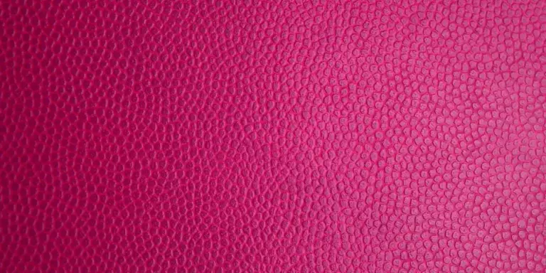 Close-up of red pebbled leather texture, illustrating the surface for a discussion on repairing and cleaning natural vs. faux leather.