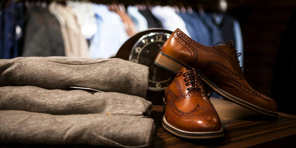 Assorted leather goods on a wooden surface, including brown dress shoes and belts, showcasing items that require pH-balanced care.