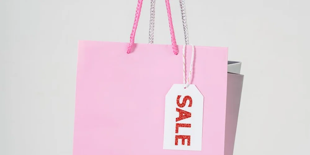 Pink handbag with a sale tag hanging from a pink strap against a light background
