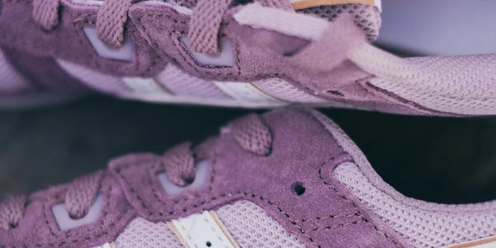 Close-up of purple suede sneakers with laces, showing the textured suede material.