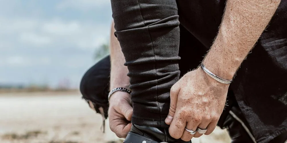 Close-up of hands adjusting a black leather sleeve, illustrating care for different leather finishes