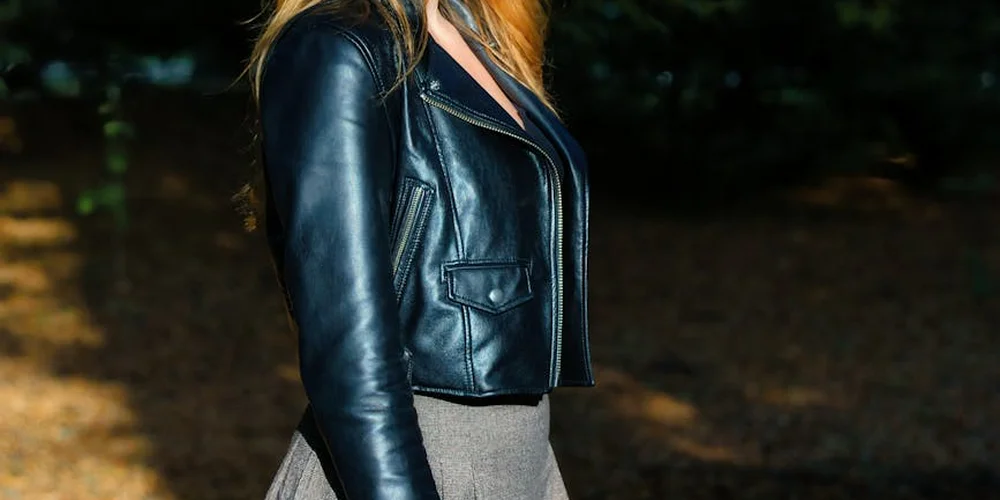 Close-up of a person wearing a black real leather biker jacket outdoors.