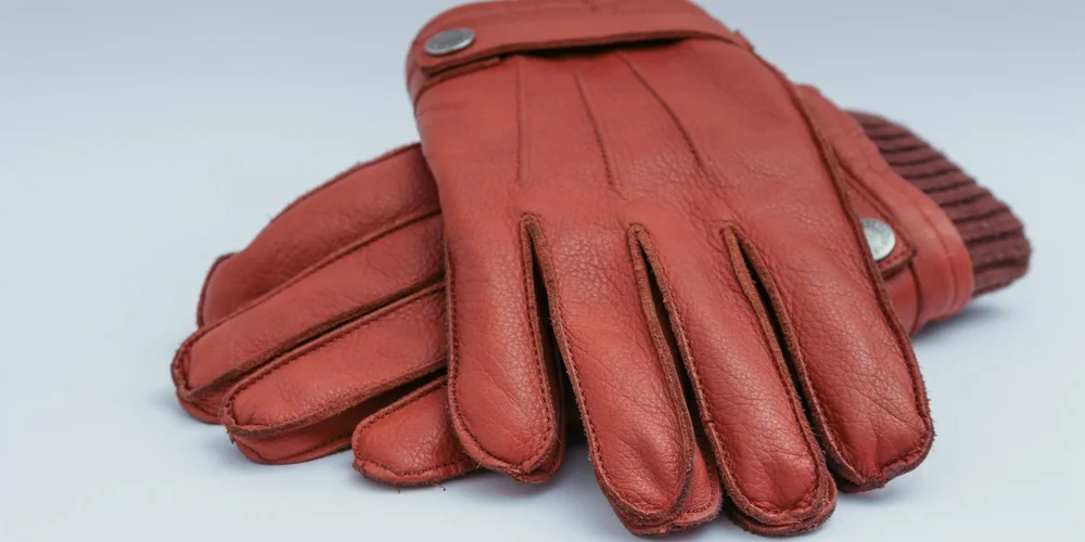 Close-up of red finished leather gloves on a pale background