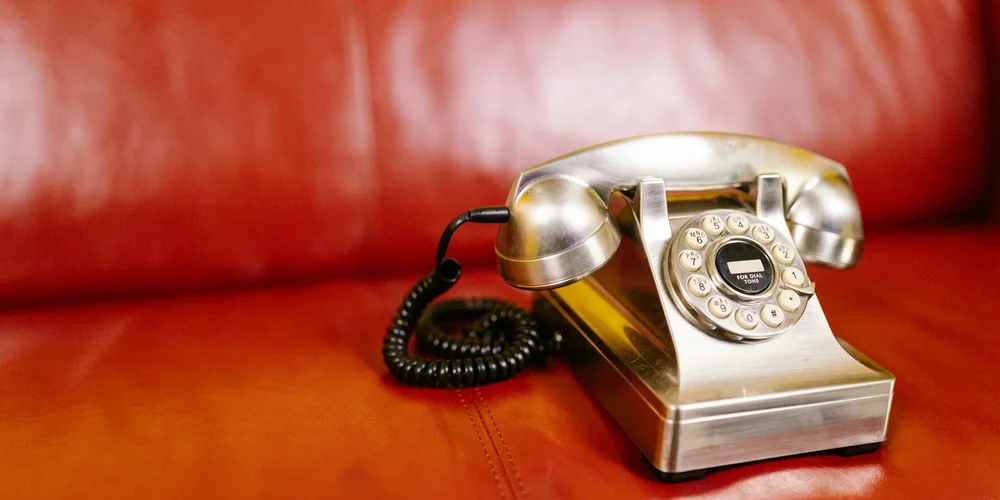 A vintage rotary telephone resting on a red leather surface, illustrating the leather that benefits from conditioning after cleaning.