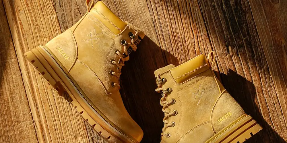 Two tan leather boots placed on a wooden surface, showing rugged construction and durable soles.