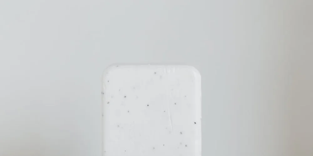 White rectangular saddle soap bar with small dark specks on a light gray background.