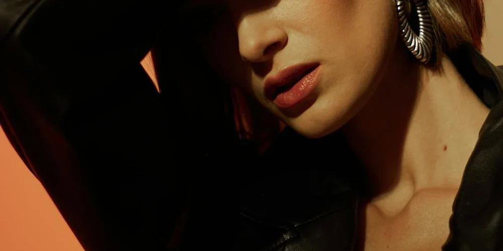 Close-up of a person wearing a black leather jacket and large hoop earring.