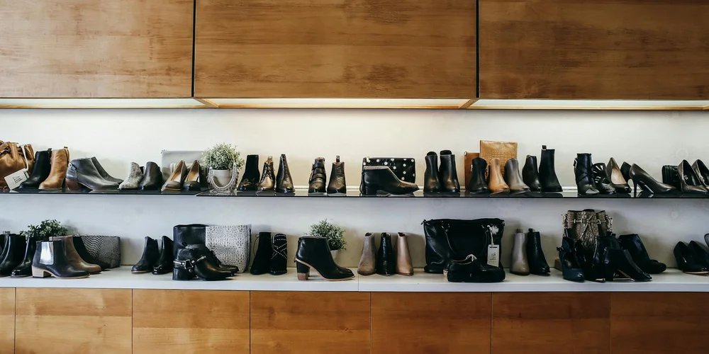 Rows of leather boots displayed on wooden shelves in a retail store.