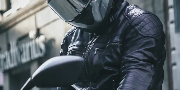 Person in a black leather motorcycle jacket and full-face helmet.
