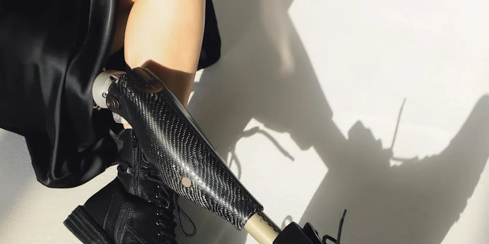 Close-up of a black textured leather boot with a metallic zipper against a bright, white background.