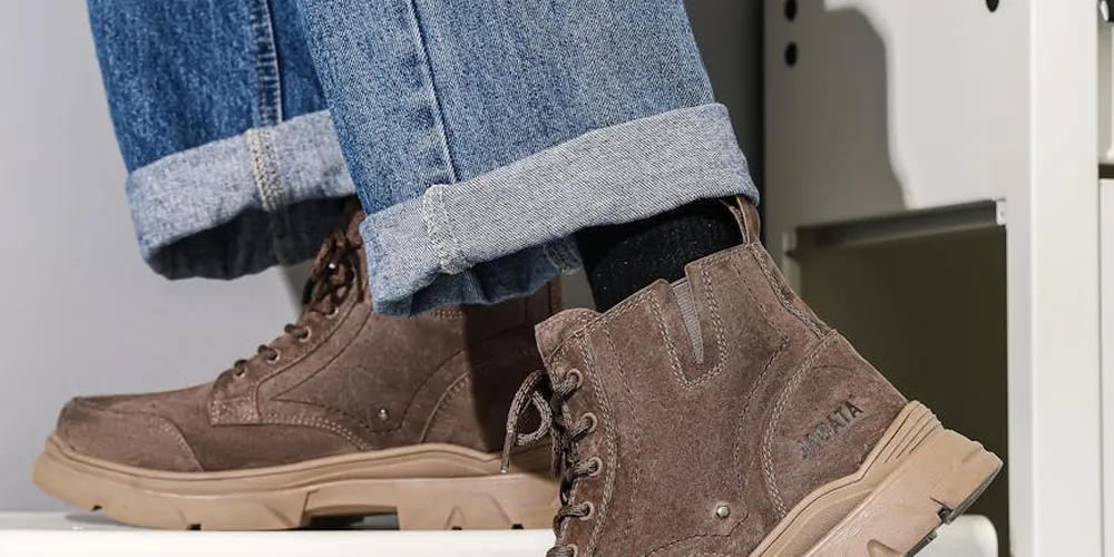Brown suede boots with beige soles and dark laces, photographed with denim jeans folded at the cuffs