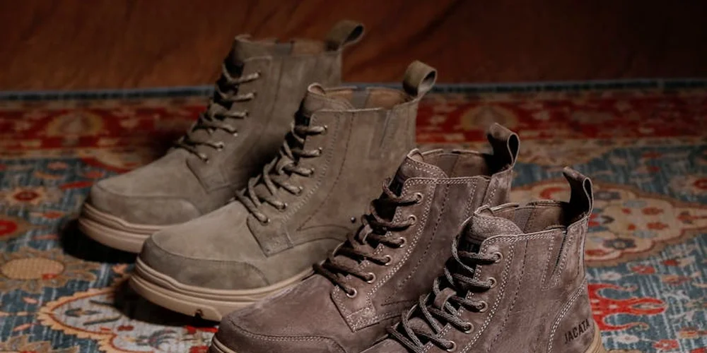 Three gray suede boots arranged in a row on a colorful patterned rug