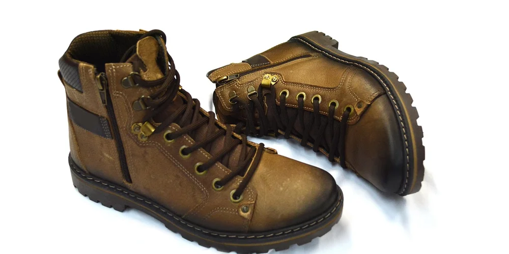 Brown suede boots with black laces and rugged soles, displayed on a white background.