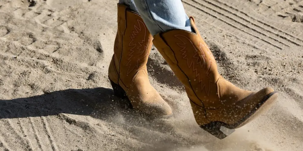 Brown suede boots walking on sandy ground, illustrating after-dye care for suede footwear