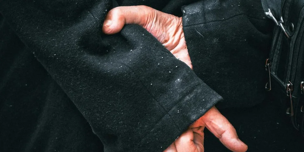 Close-up of a black suede jacket's textured surface with a sleeve and zipper.