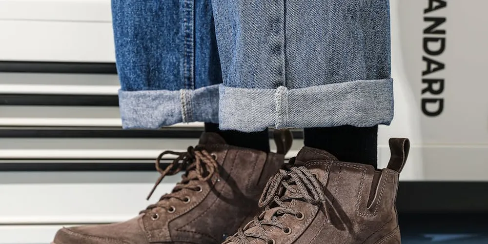 Close-up of brown suede ankle boots with rolled denim jeans, highlighting the suede texture.