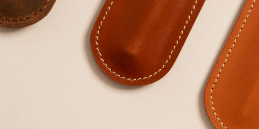 Close-up of tan suede leather items with visible white stitching