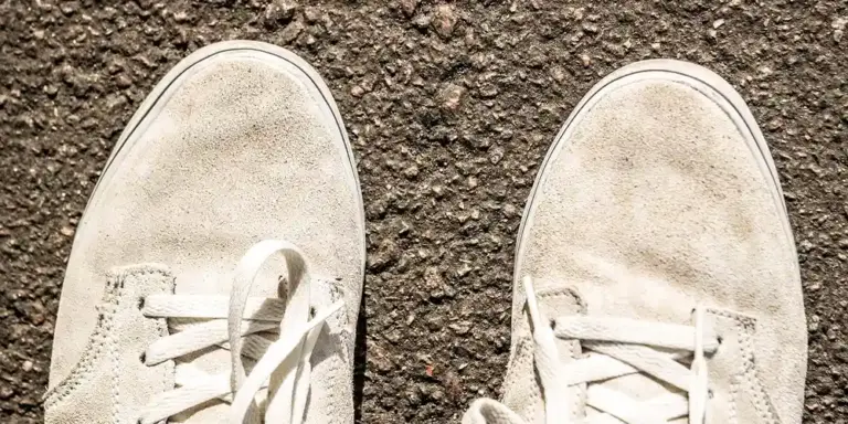 Beige suede sneakers resting on a rough, dark surface