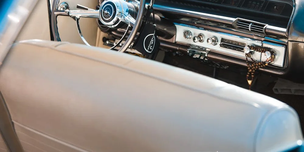 Close-up of a vintage car interior showing a leather seat and a chrome dashboard.