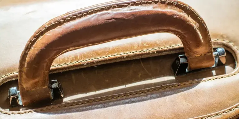 Close-up of a brown vintage leather bag handle with visible stitching and wear
