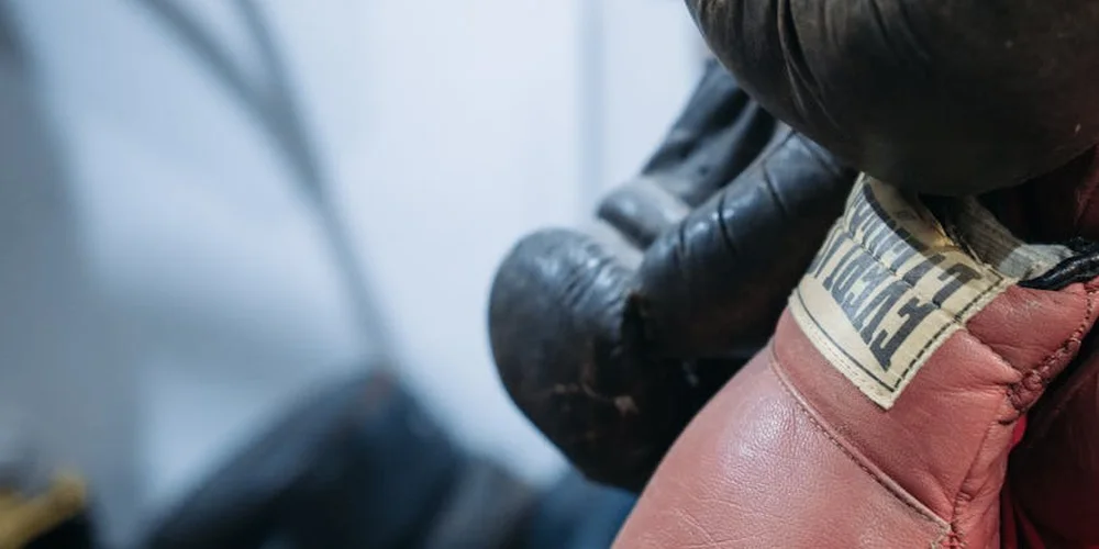 Close-up of gloved hands examining a vintage leather item for restoration