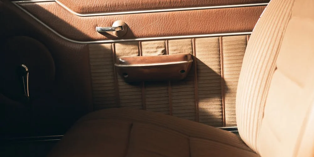 Close-up of a vintage car's brown leather door panel and seat upholstery