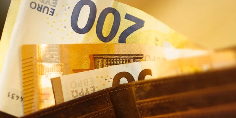 Brown leather wallet with stacks of €200 banknotes spilling out.