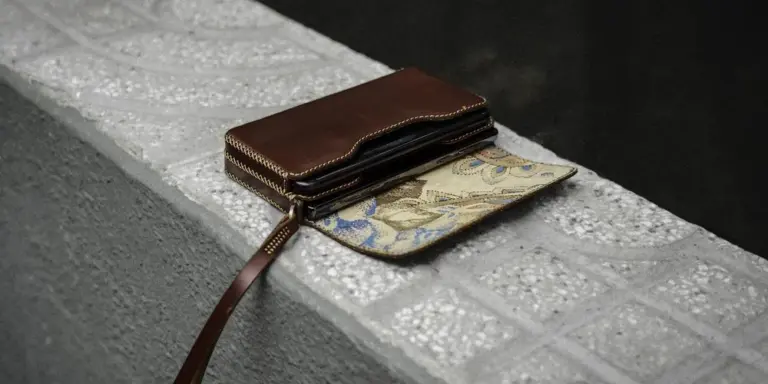 Brown leather wallet resting on a textured concrete surface.